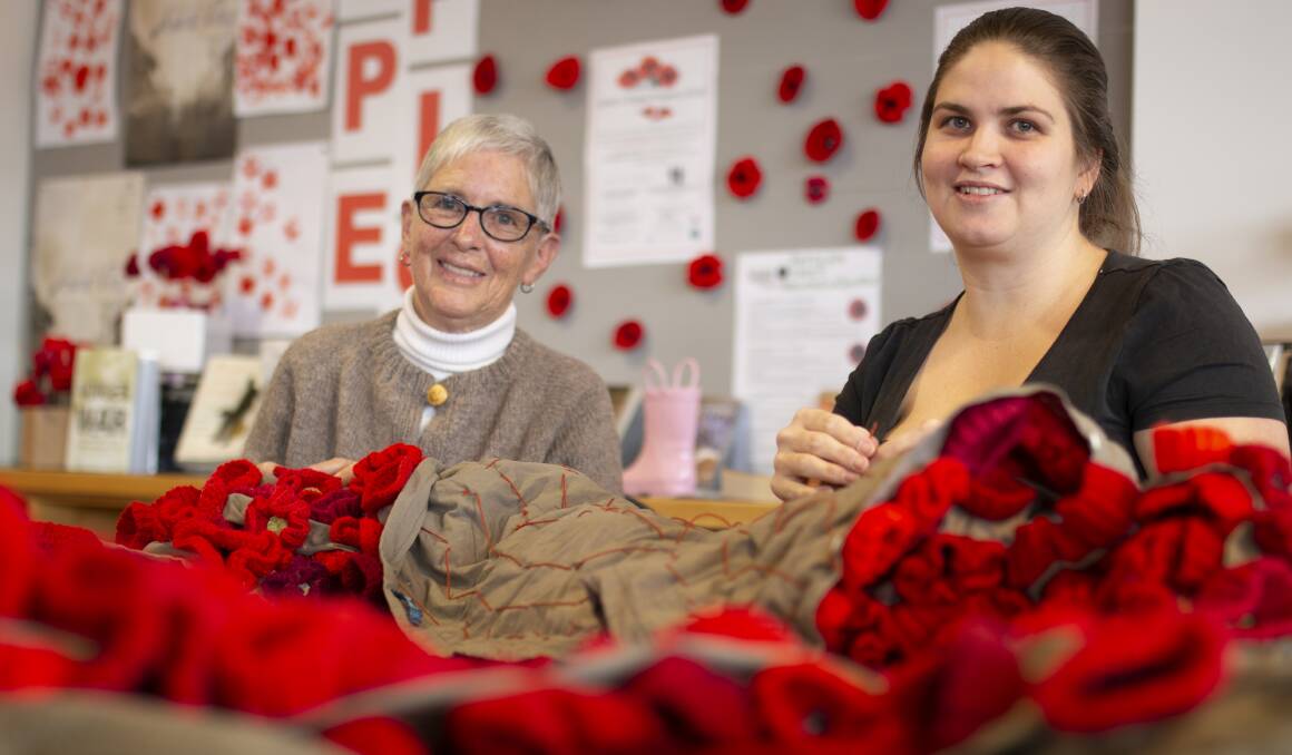 Barb Wignall and Hannah Kruger, of Junee's CWA, have the enormous task of attaching 3,000 handmade poppies for Remembrance Day. Picture: Emma Horn